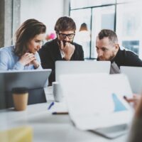 three people gathered around a laptop