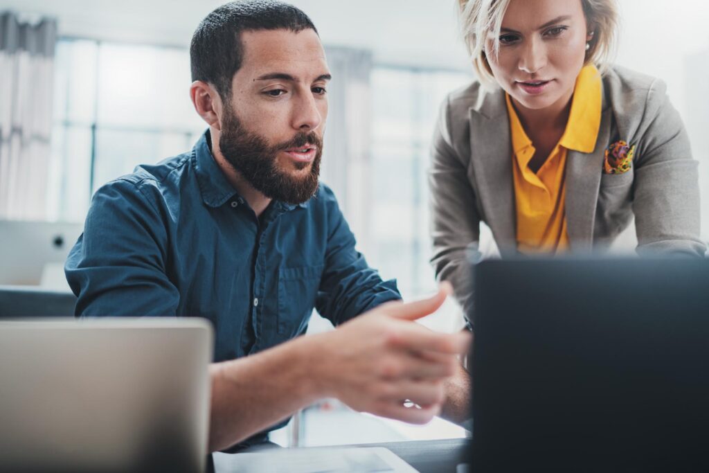 consultant explaining something on a laptop screen to a colleague
