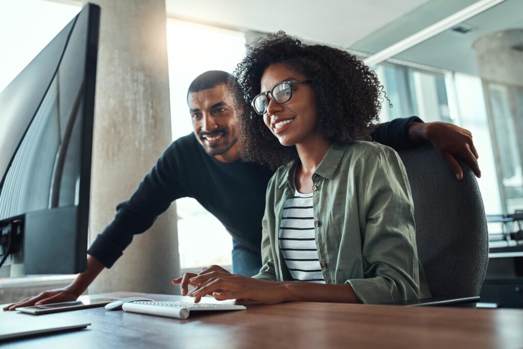 a man and woman looking at the desktop computer monitor