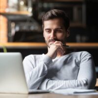 man thinking about work while looking at his laptop