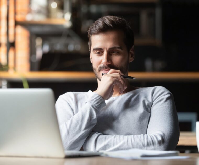 man thinking about work while looking at his laptop