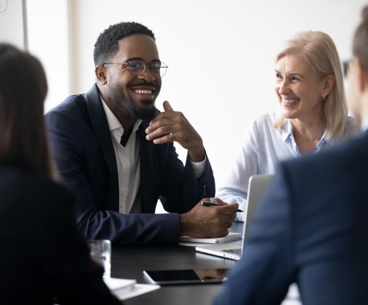 man speaking with his colleagues around a meeting table