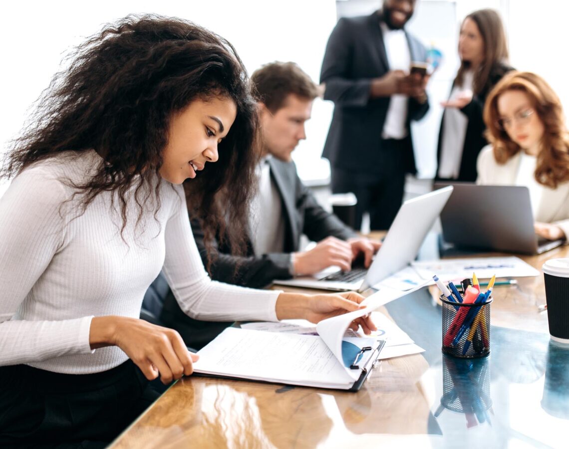 woman working at a table with colleagues in the background