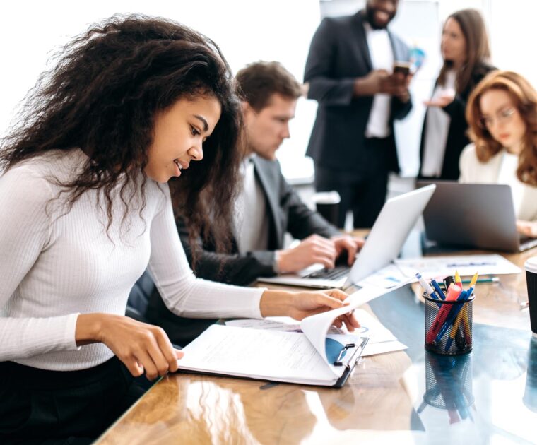 woman working at a table with colleagues in the background