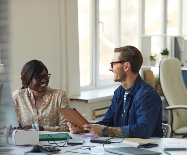 two colleagues discuss a report at their desks