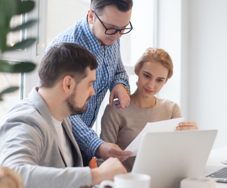 three colleagues working on a laptop and reviewing a document