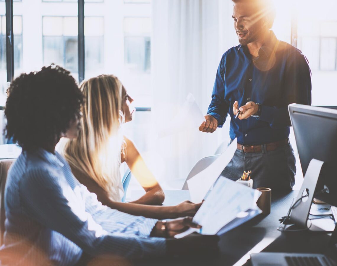 a man speaking with two women in an office