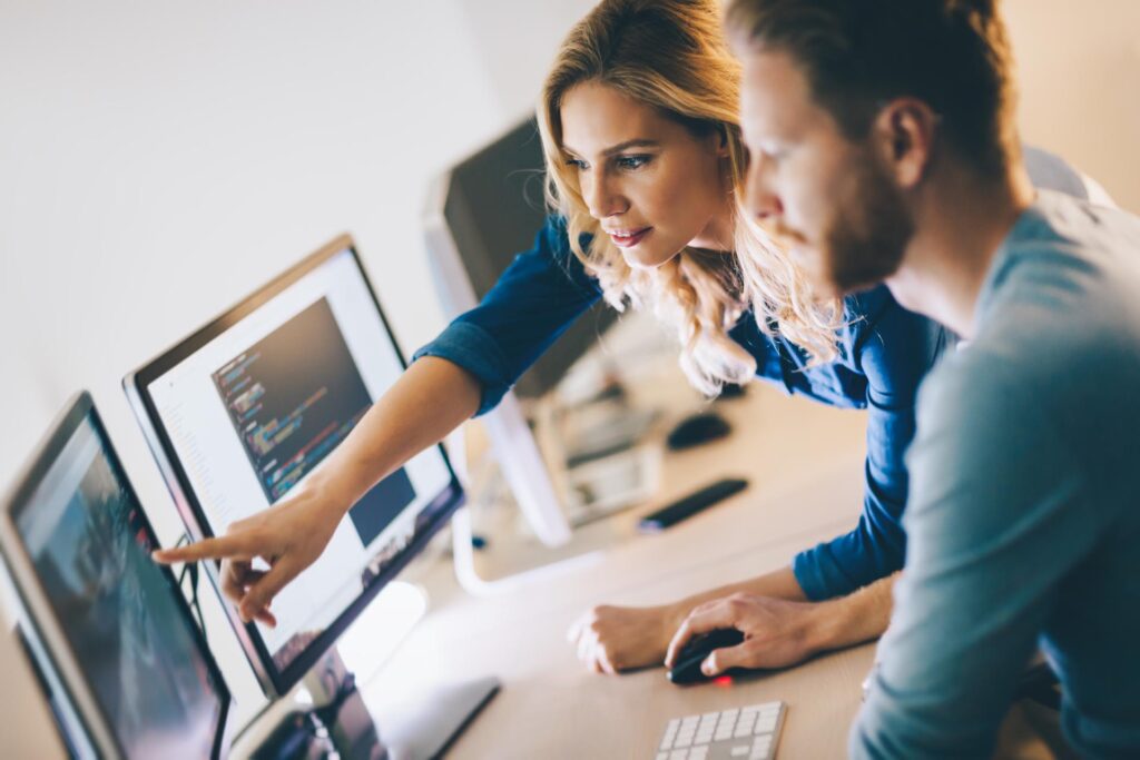 woman pointing at a screen explaining something to a colleague