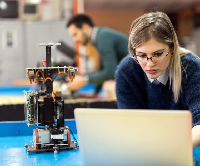 woman working on a robotics project using a laptop