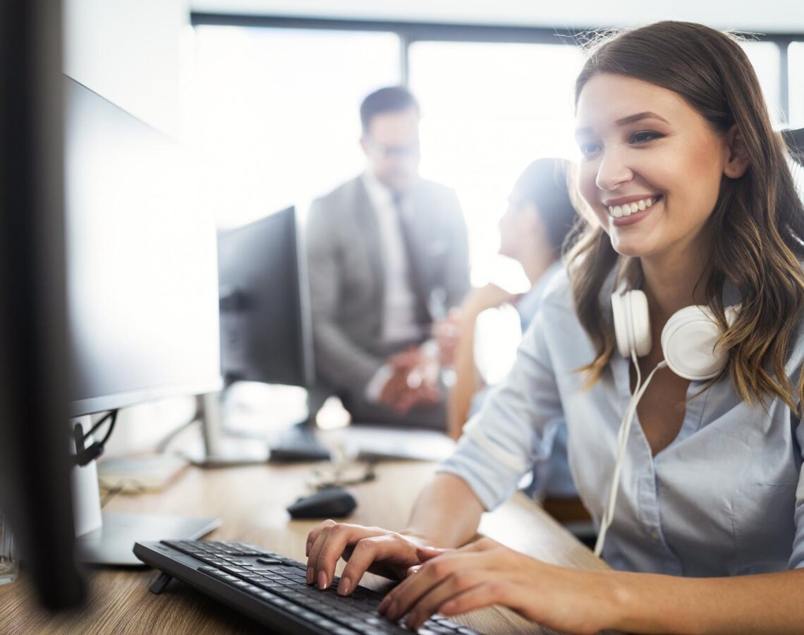 woman wearing headphones working on a desktop computer
