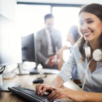 woman wearing headphones working on a desktop computer