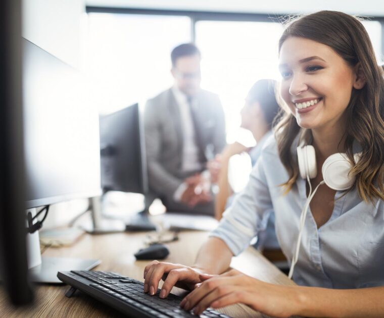 woman wearing headphones working on a desktop computer