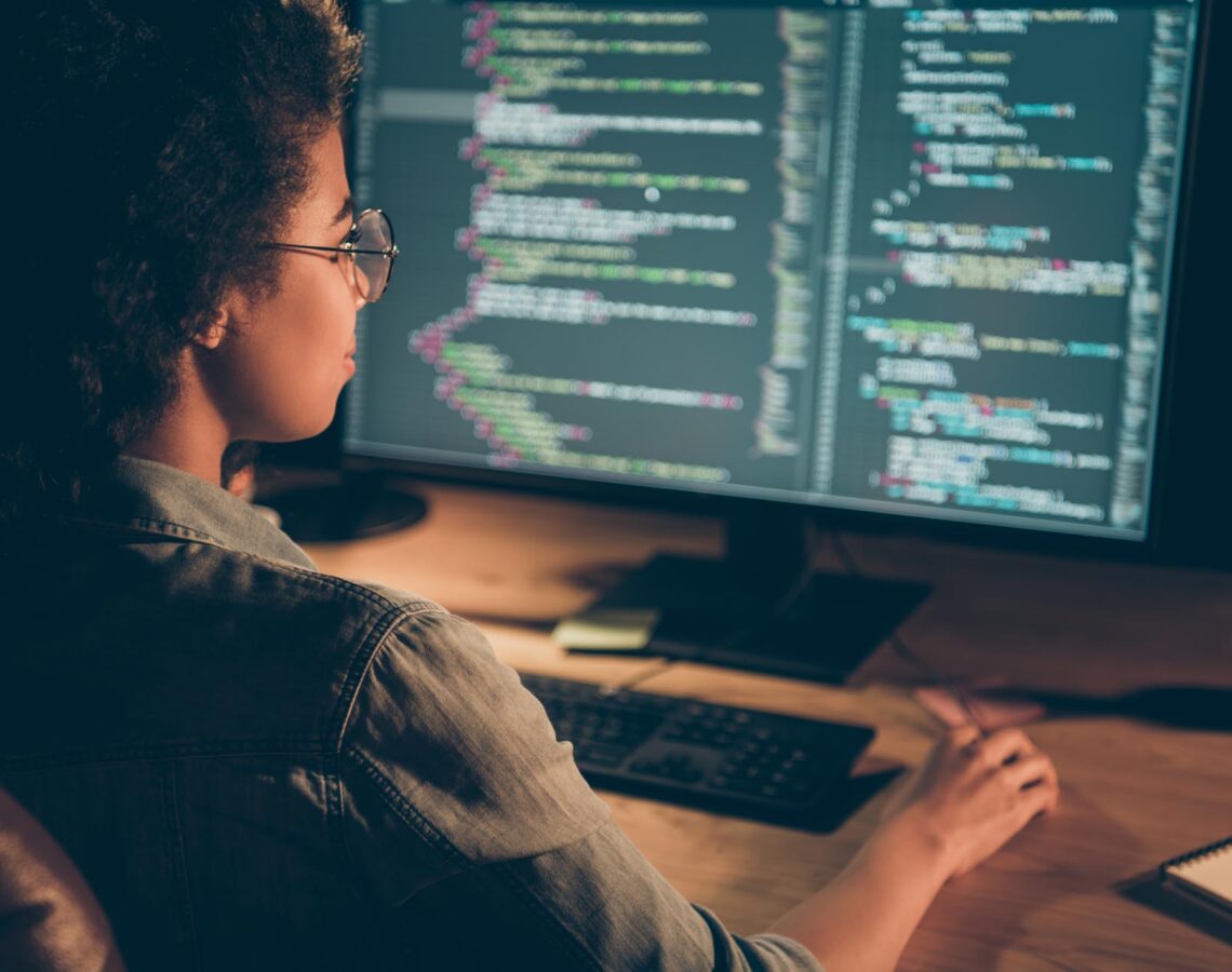 t-shaped technologist writing lines of code at a desktop computer