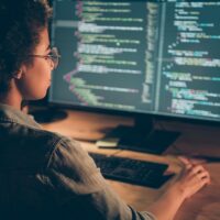 t-shaped technologist writing lines of code at a desktop computer