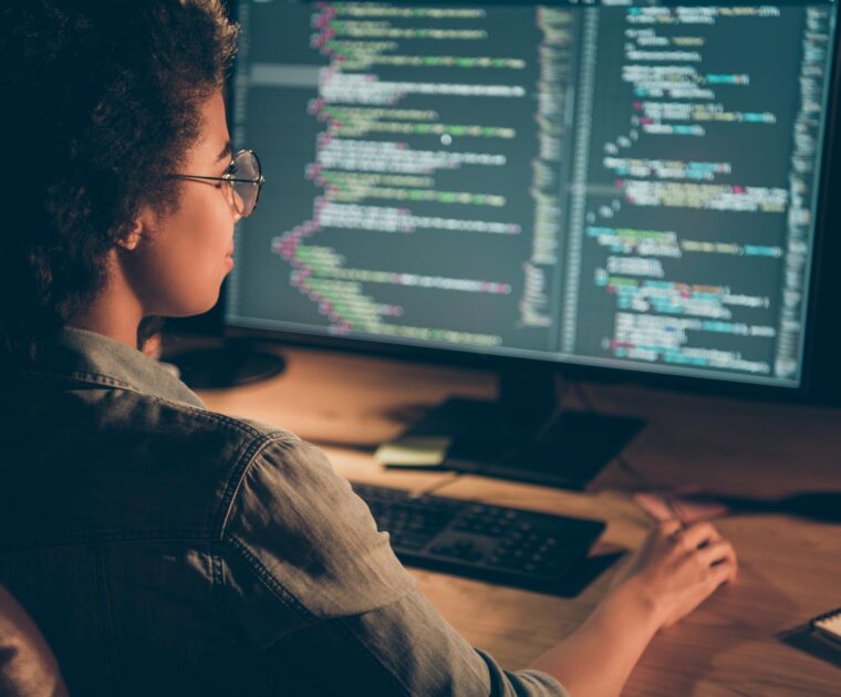 t-shaped technologist writing lines of code at a desktop computer