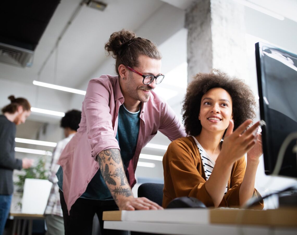 a woman explaining something to a colleague at her desk
