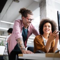 a woman explaining something to a colleague at her desk