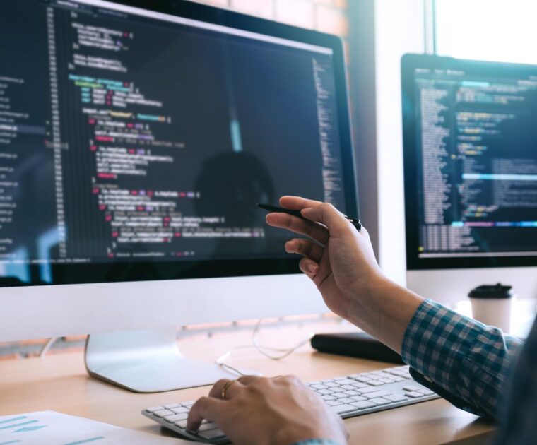 man writing code at desktop computer
